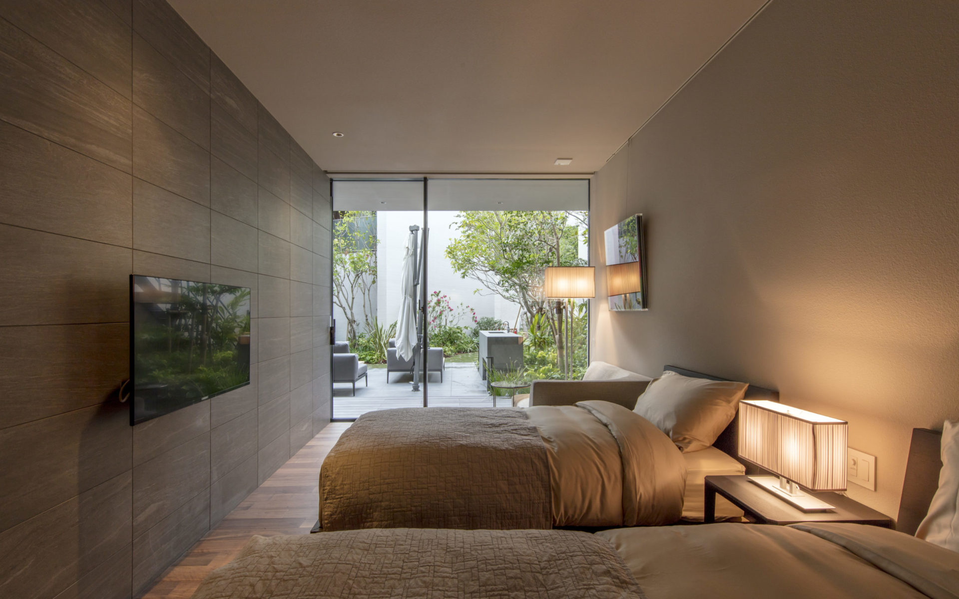 シモンズのベッドマットを利用した落ち着いた雰囲気のベッドルーム 窓からはリゾート風の中庭が見える。