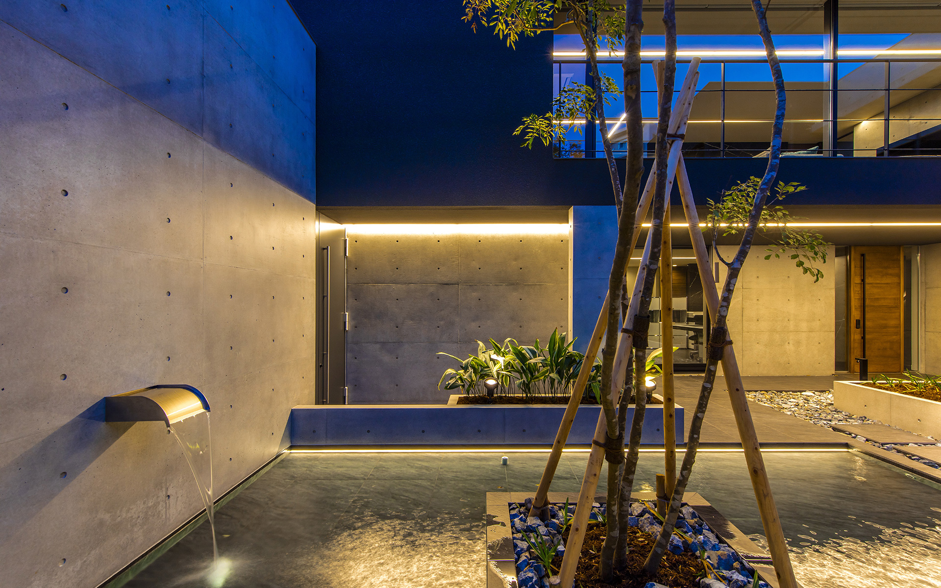 関西設計事務所によるライン照明で水平線の強調されたリゾートホテルライクな水盤のある中庭の夜景